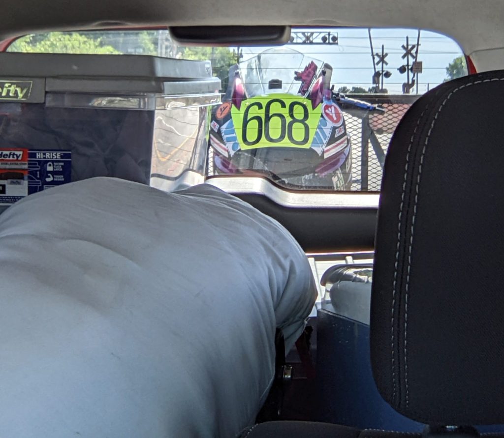 First motorcycle race preparation is over. Rear view mirror shot of the racing motorcycle in the trailer behind the Kia